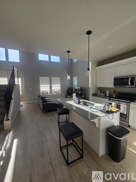 A kitchen with a bar stool and a trash bin.