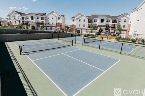 A tennis court is surrounded by apartment buildings.