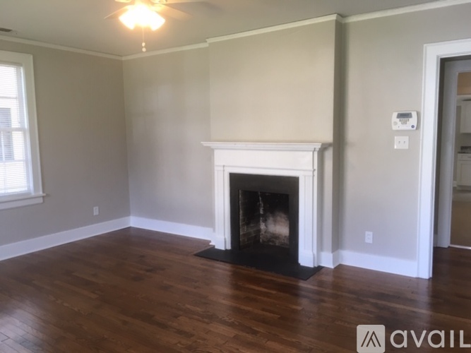 A living room with a fireplace and wooden floors.
