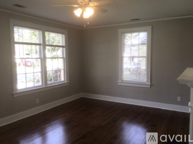 A room with a ceiling fan and two windows.