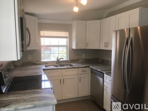 A kitchen with white cabinets and a marble countertop.