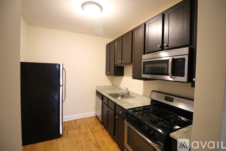 A kitchen with black appliances and wooden floors.