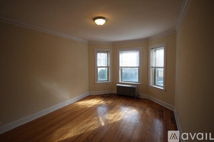 A room with wooden floors and three windows.
