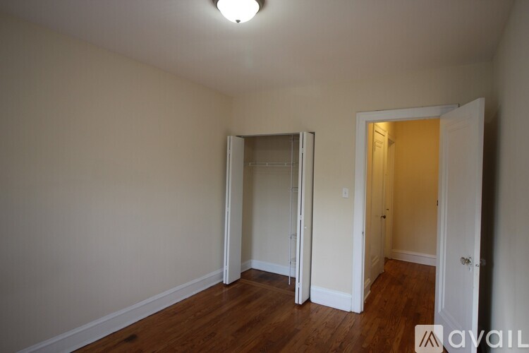 A room with a wooden floor and white walls, with a doorway leading to another room.
