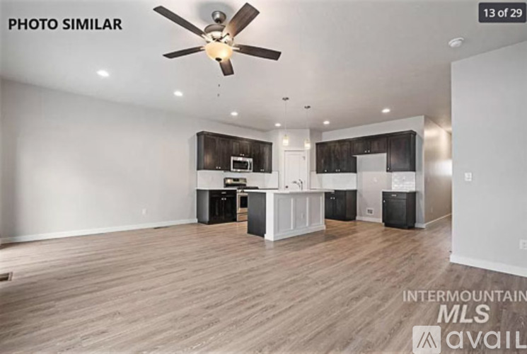 A photo of an empty room with a ceiling fan and wooden flooring.