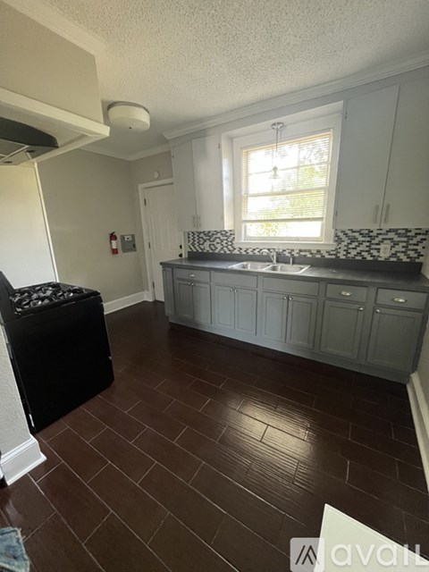 A kitchen with white cabinets and a black trash can.