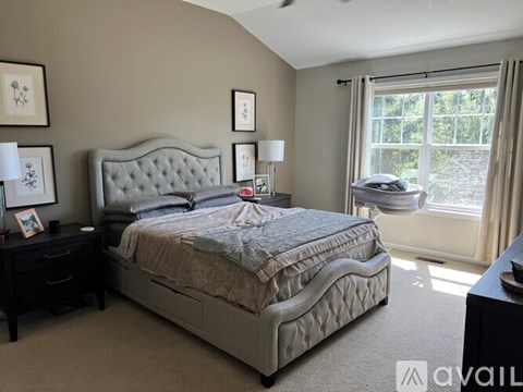A bedroom with a large bed and a window overlooking a garden.