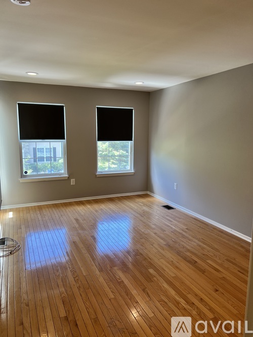 A room with wooden floors and two windows.