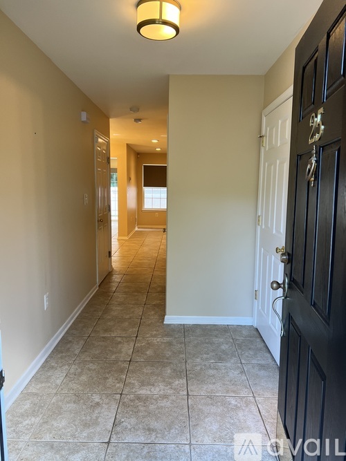 A hallway with a black door and tiled floor.