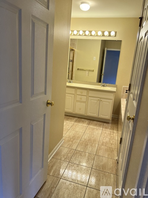 A bathroom with a white door and a mirror above a sink.