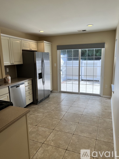 A kitchen with a black refrigerator and white cabinets.