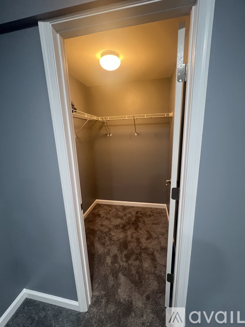 A small, empty room with a carpeted floor and a single light bulb on the ceiling.