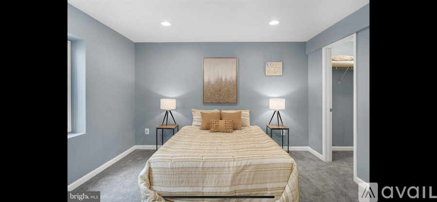 A bedroom with a bed, two lamps, and a painting on the wall.