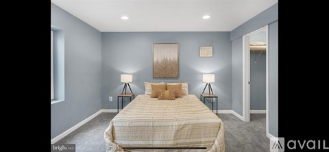 A bedroom with a bed, two lamps, and a painting on the wall.