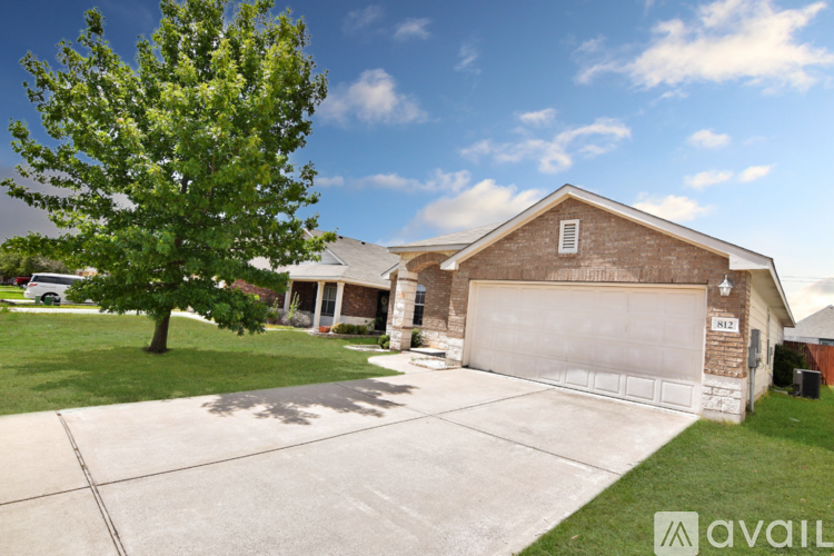 A house with a garage and a tree in front of it.