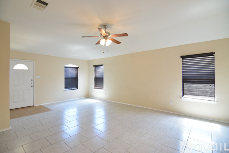 A spacious room with a ceiling fan and three windows.