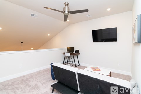 A living room with a grey couch and a black television mounted on the wall.