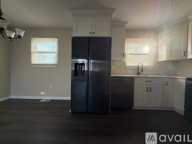 A black refrigerator in a kitchen with white cabinets.