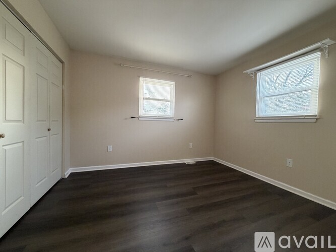 A room with wooden floors and two windows.