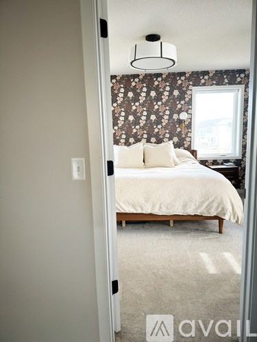 A bedroom with a floral wallpaper and a bed with a wooden frame.