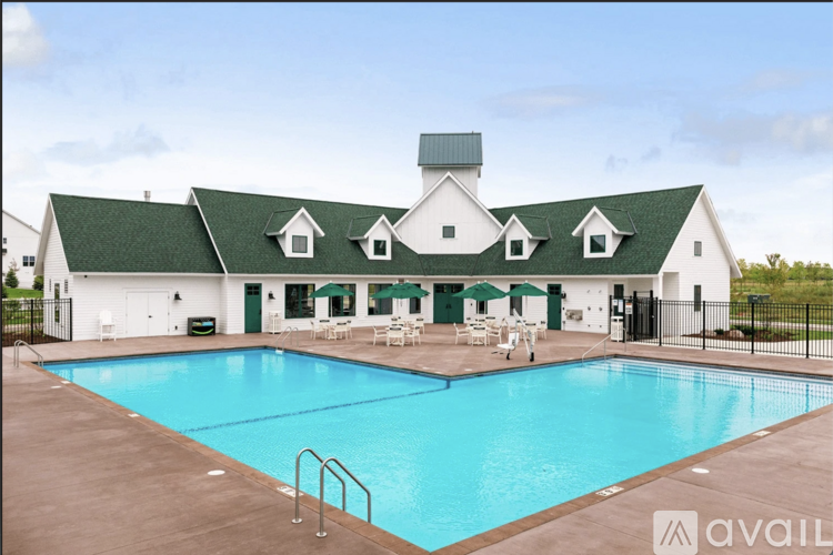 A large white building with a green roof and a pool in front.