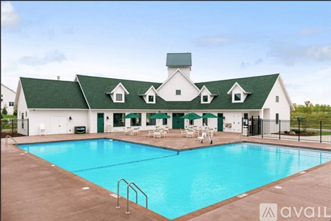 A large white building with a green roof and a pool in front.
