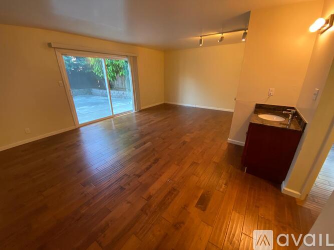 A room with wooden flooring and a sliding glass door leading outside.