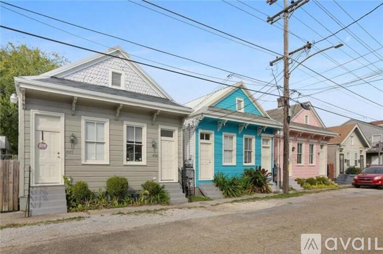 A house with a blue door is in front of a house with a pink door.