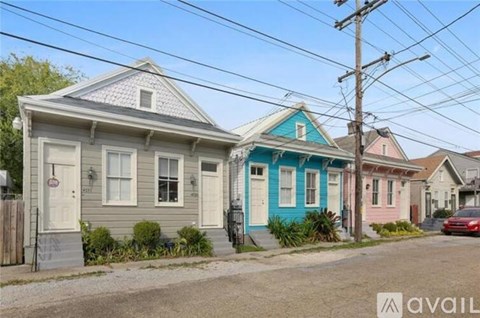 A house with a blue door is in front of a house with a pink door.