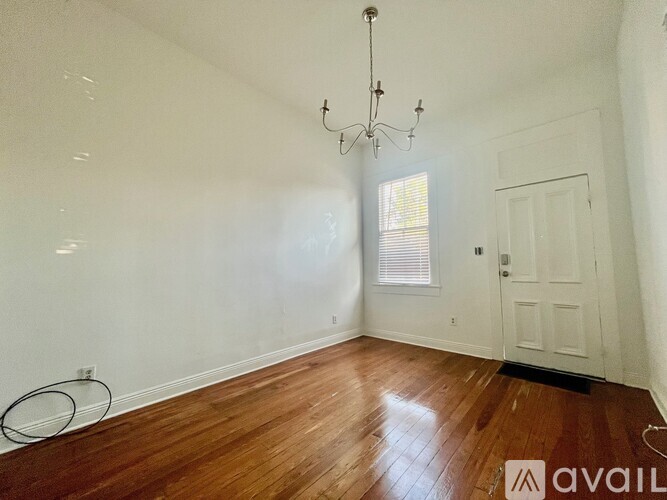 A room with a chandelier, a door, and a window.
