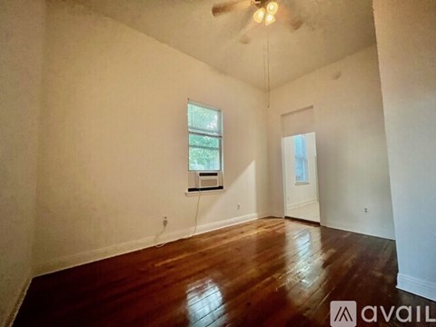 A room with wooden floors and a window with a view of a building outside.