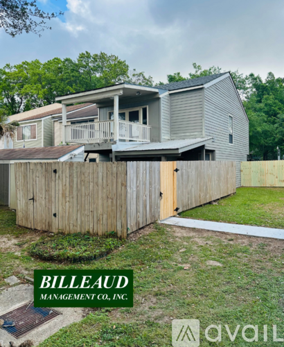A house with a wooden fence and a sign that says "BILLEAUD MANAGEMENT CO. INC."