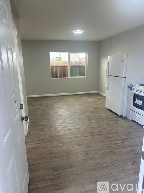 A kitchen with a white fridge and wooden flooring.