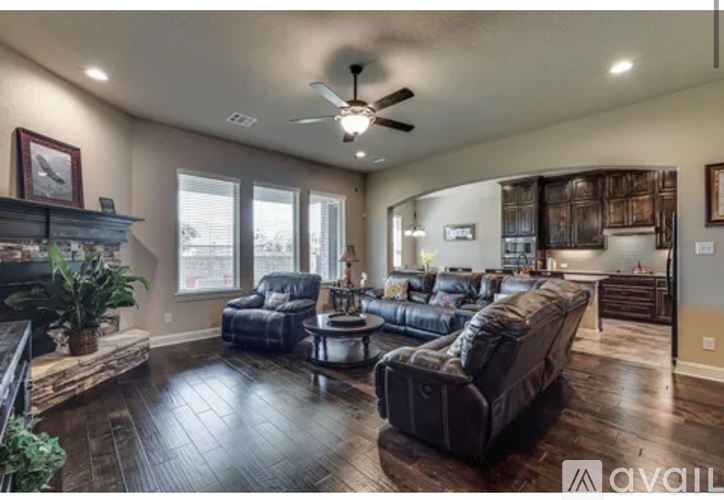 A living room with a dark brown leather couch and a wooden floor.