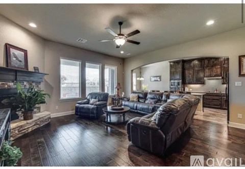 A living room with a dark brown leather couch and a wooden floor.