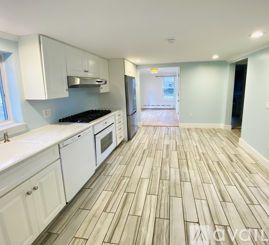 A kitchen with white cabinets and a wooden floor.