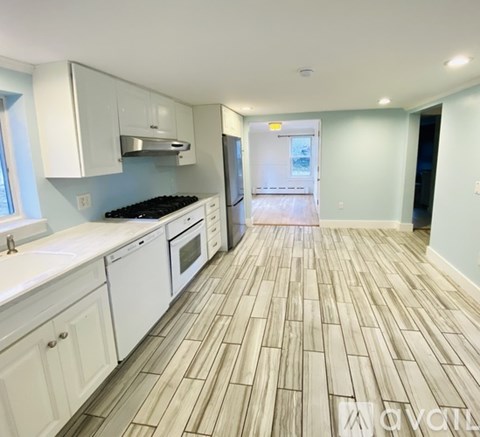 A kitchen with white cabinets and a wooden floor.