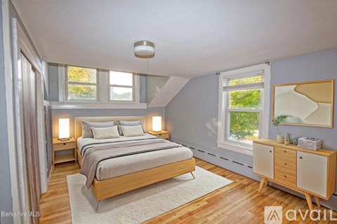 A bedroom with a bed, nightstands, and a window.