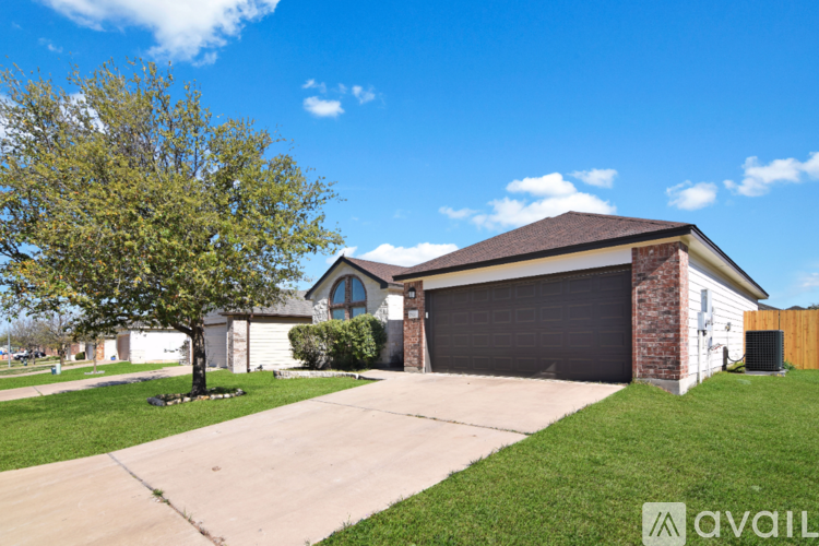 A house with a garage and a tree in front.