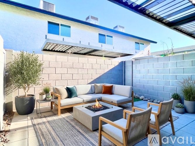 A patio with a couch, chairs, and a fire pit.