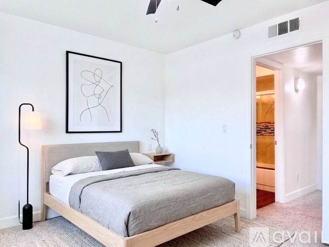 A bedroom with a bed, a lamp, and a picture on the wall.