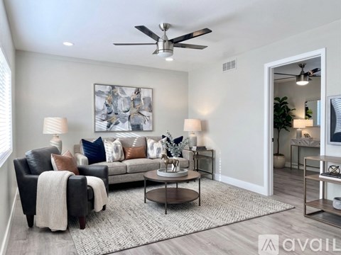 A living room with a black leather couch, a coffee table, and a painting on the wall.