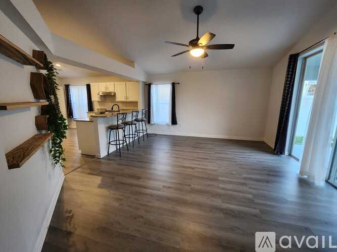 A spacious room with wooden flooring and a ceiling fan.