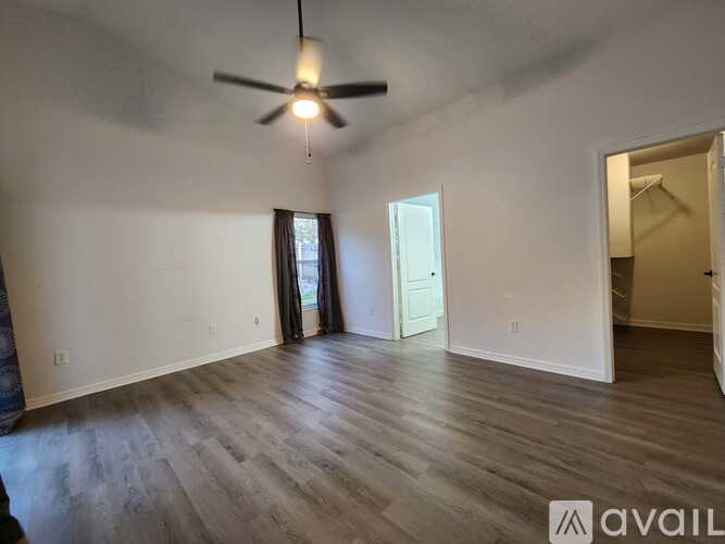 A room with a ceiling fan and wooden flooring.