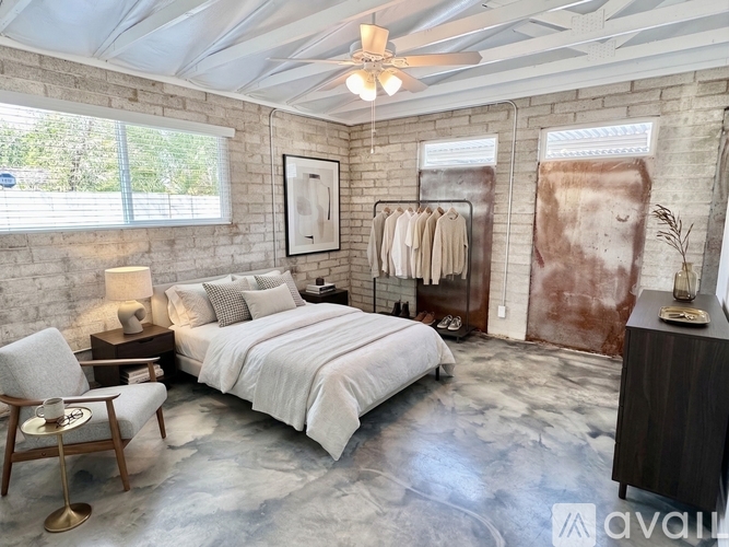 A bedroom with a bed, chair, and a ceiling fan.