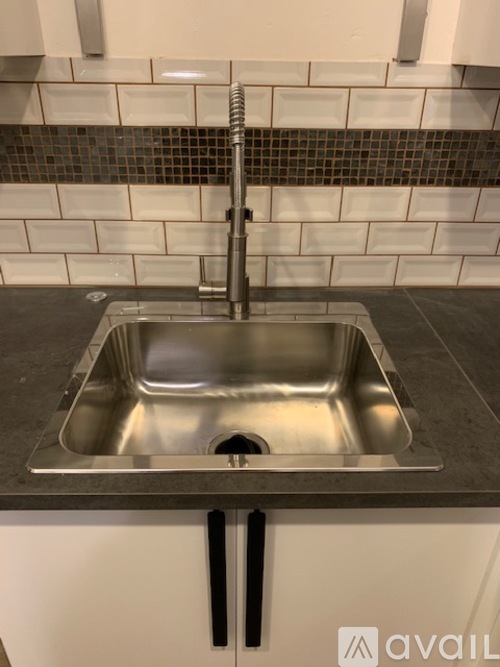 A kitchen sink with a chrome faucet and a tiled backsplash.
