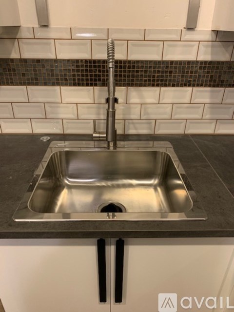 A kitchen sink with a chrome faucet and a tiled backsplash.
