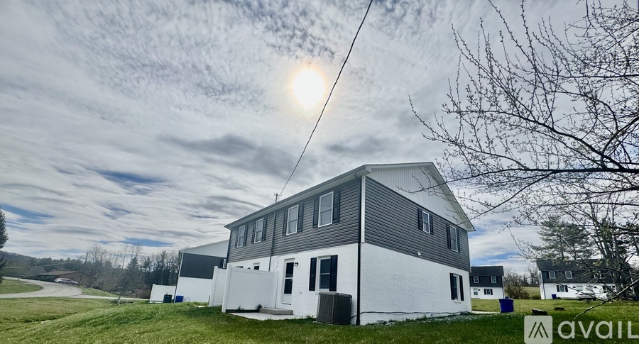 A house with a grey roof and white walls is available for rent.
