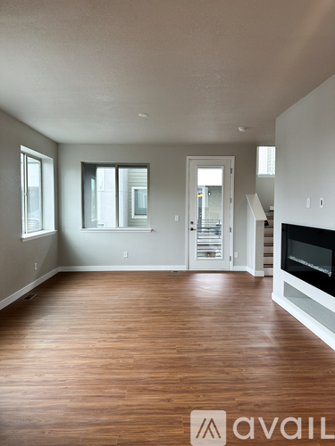 A spacious living room with wood flooring and a fireplace.