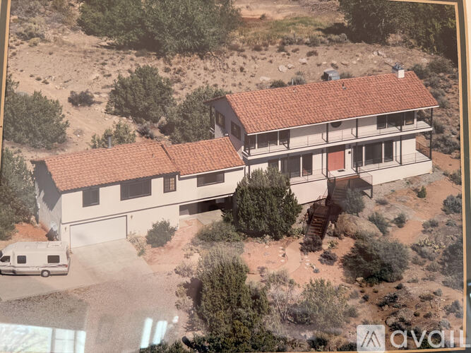 A house with a red tile roof is surrounded by trees and bushes.